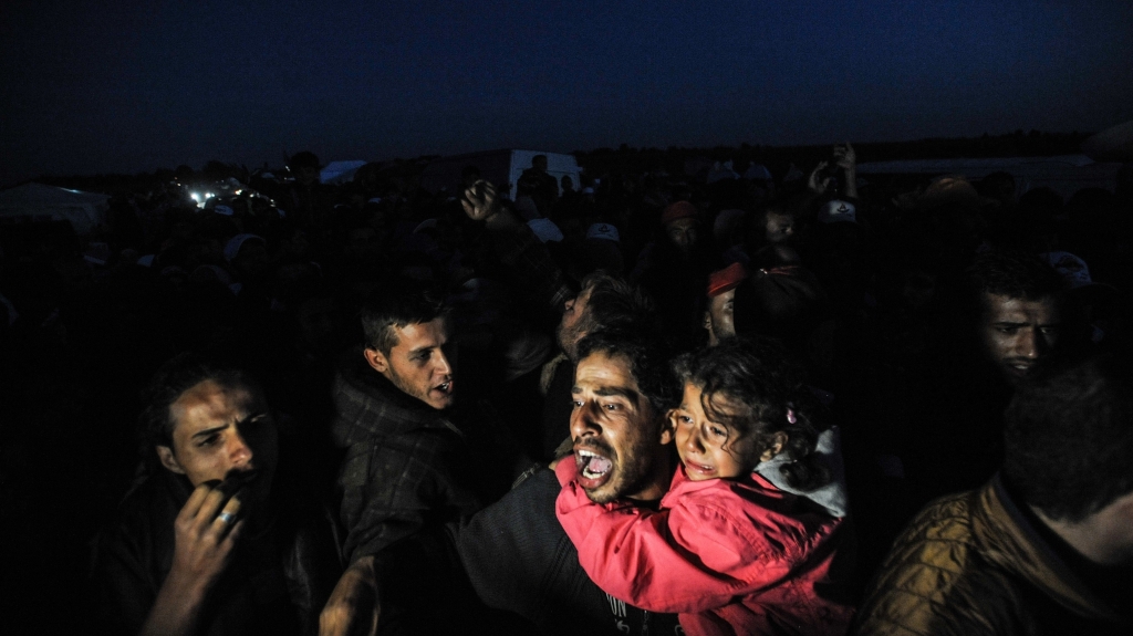 Hungarian police officers stop a group of refugees near a makeshift camp for asylum seekers in Roszke southern Hungary in September 2015