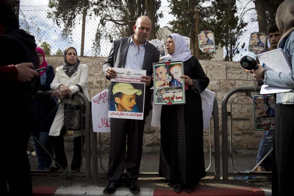 Suha and Hussein Abu Khdeir center parents of Mohammed Abu Khdeir hold posters with his portrait after the reading of the verdict in his killing at the Jerusalem District Court Monday Nov. 30 2015. The court on Monday convicted two Israeli youths