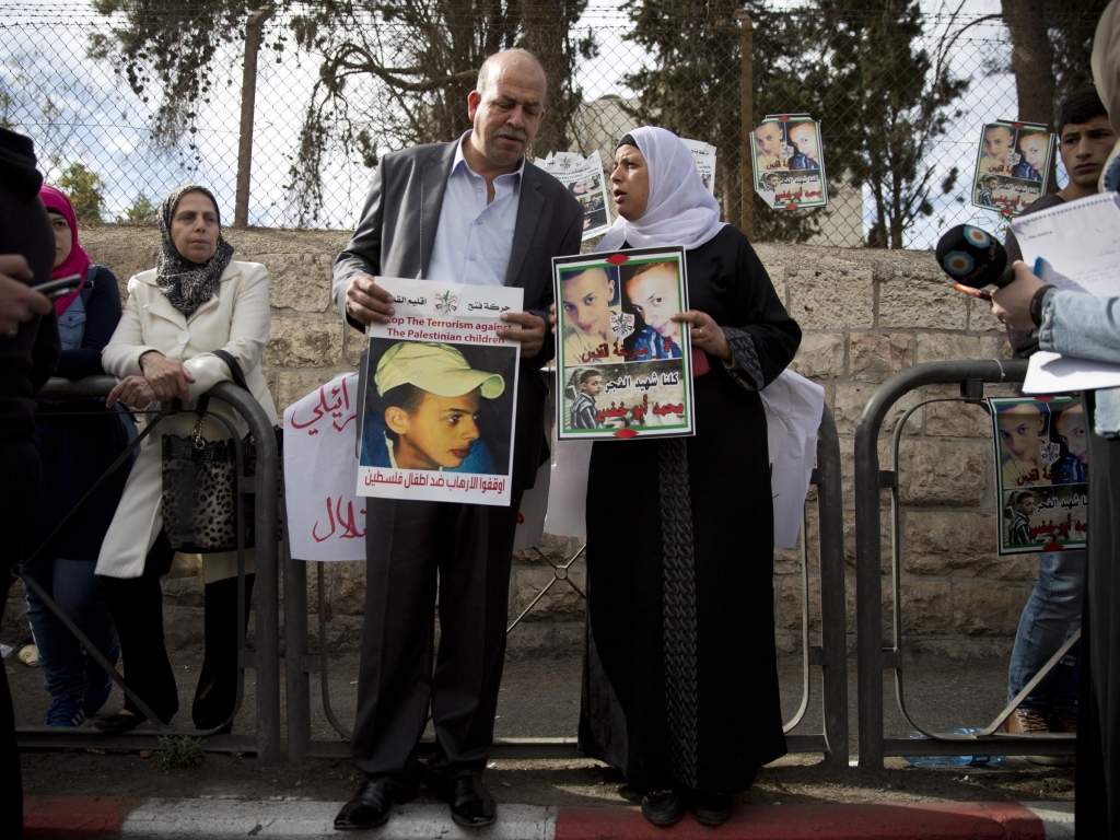 Hussein and Suha Abu Khdeir, parents of 16-year-old Palestinian victim Mohammed Abu Khdeir hold posters with their son's portrait after the verdict was read in Jerusalem