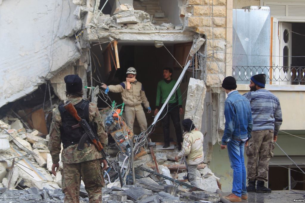 FILE- A civil defense member gestures toward a rebel fighter as they search for survivors at a site hit by what activists said were airstrikes carried out by the Russian Air Force in Idlib Syria Dec. 20 2015