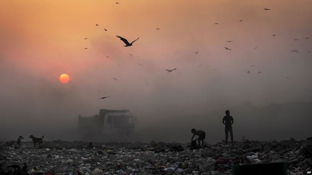 FILE A thick blanket of smoke is seen against the setting sun as young ragpickers search for reusable material at a garbage dump in New Delhi India Oct. 17 2014