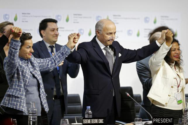 French Foreign Affairs Minister Laurent Fabius, President-designate of COP21 and Christiana Figueres, Executive Secretary of the UN Framework Convention on Climate Change hold hands as they react during the final plenary session at the World Clim