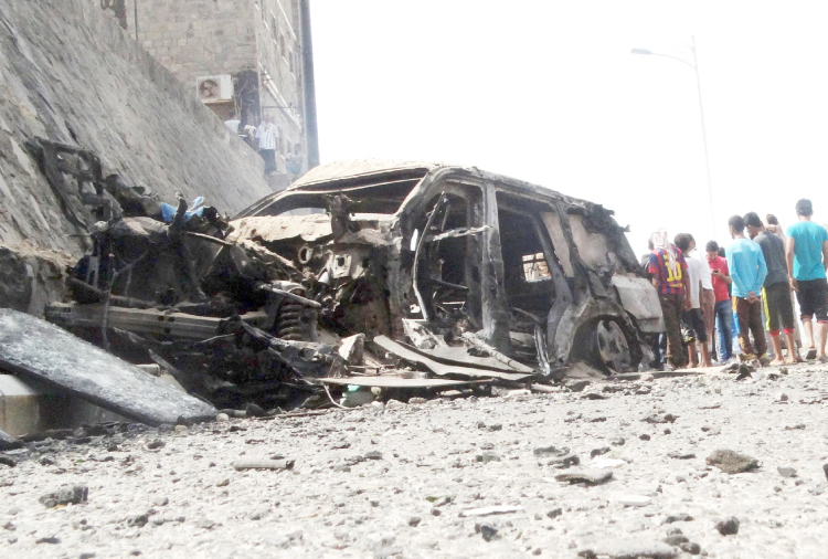 People gather at the site of a car bomb attack that killed the governor of Yemen