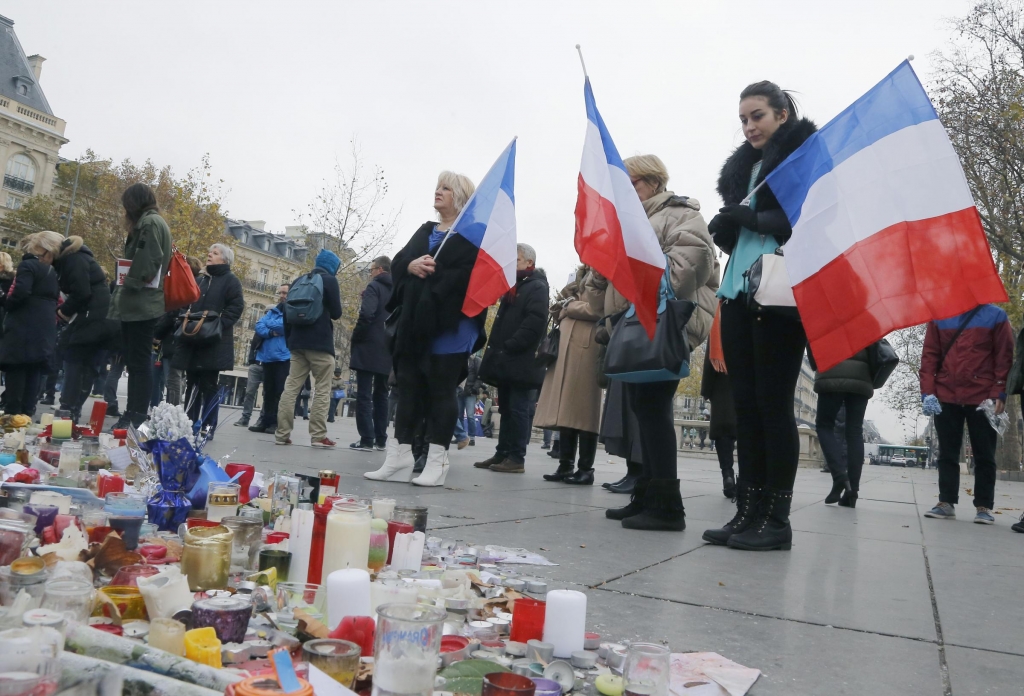 People hold French flags on the Place de la Republique in Paris