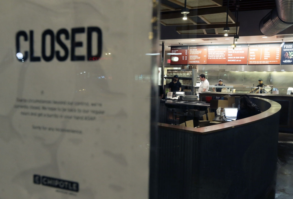 People stand inside a closed Chipotle restaurant on Monday in the Cleveland Circle neighborhood of Boston