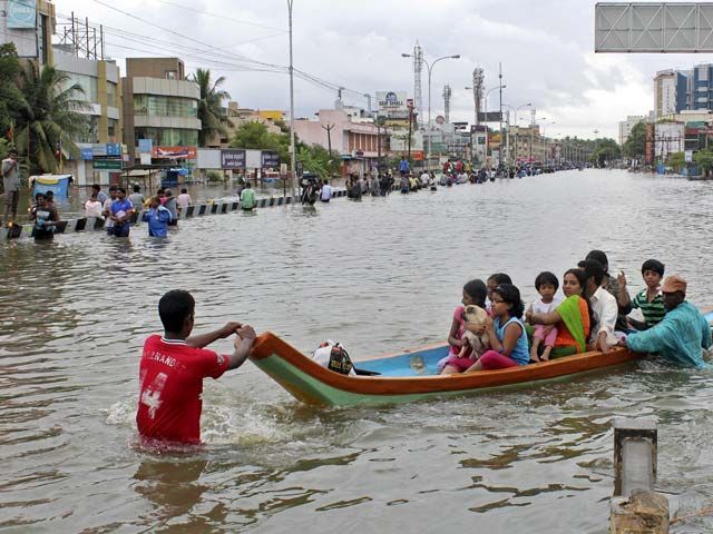 People travel on a boat as they move to safer places through a flooded road in Chennai India