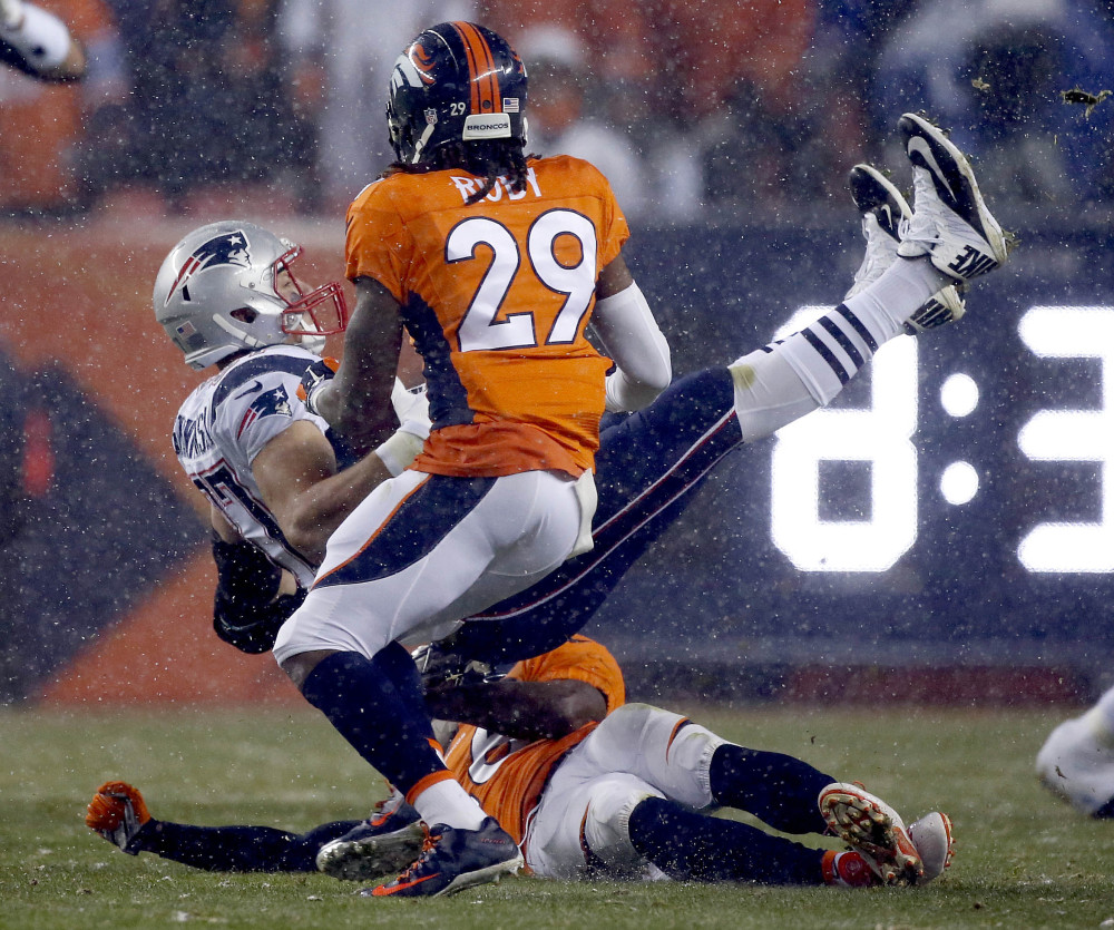 Rob Gronkowski is upended by Denver safeties Darian Stewart on ground and Bradley Roby. Later in Sunday night’s game Gronkowski was carted off the field