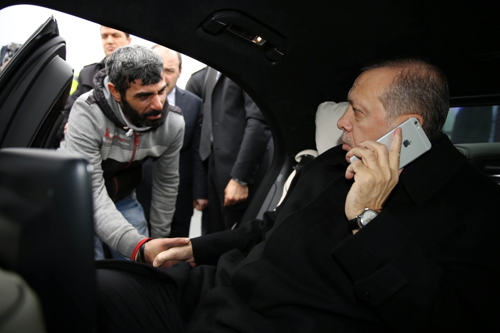 Turkish President Recep Tayyip Erdogan right takes Vezir Cakras by hand while speaking on his mobile phone inside his car stationed over the Bosporus Bridge in Istanbul Friday Dec. 25 2015. Erdogan’s office says the Turkish president has talked Cak