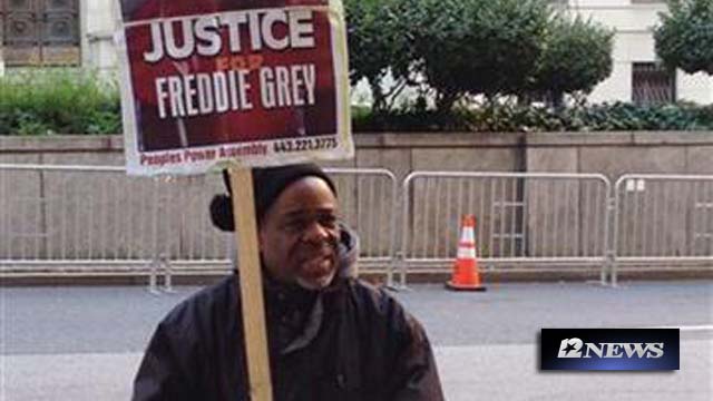 Demonstrator Arthur Johnson carries a sign advocating justice for Freddie Gray on Monday Dec. 7 2015 outside the courthouse in Baltimore where the trial of Offcer William Porter enters its second week