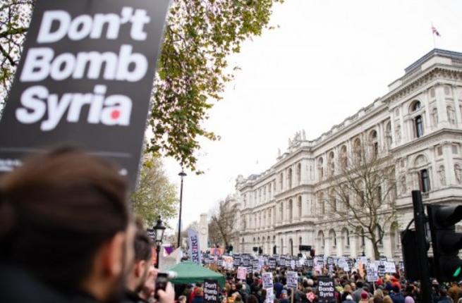 Protesters stand outside Downing Street in central London carrying signs that say