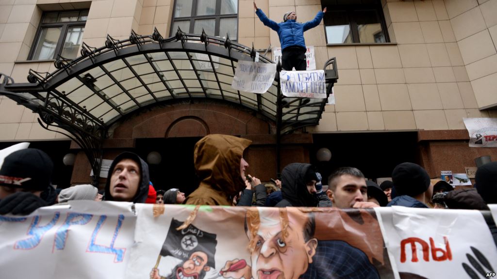 Russian protesters hold up a poster showing Turkish President Recep Tayyip Erdogan as a puppet of Islamic State militants during a rally in front of the Turkish Embassy in Moscow on November 25