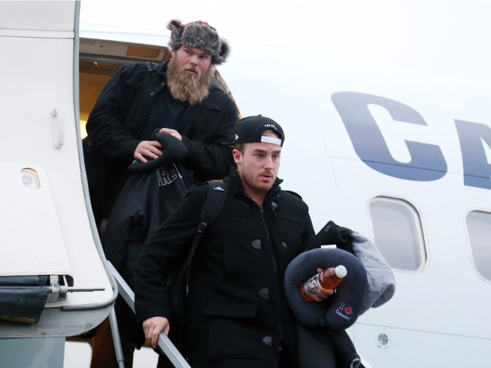 Jon Gott top and punter Ronniei Pfeffer of the Ottawa Redblacks exit the plane in Ottawa after returning from a loss in the Grey Cup game at Winnipeg