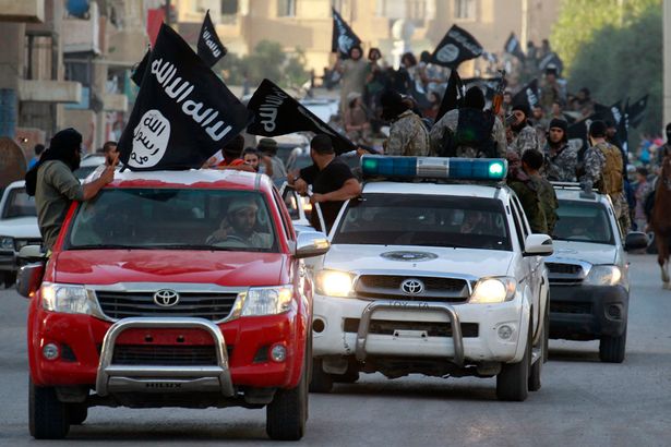 Militant Islamist fighters waving flags travel in vehicles as they take part in a military parade along the streets of Syria's northern Raqqa province