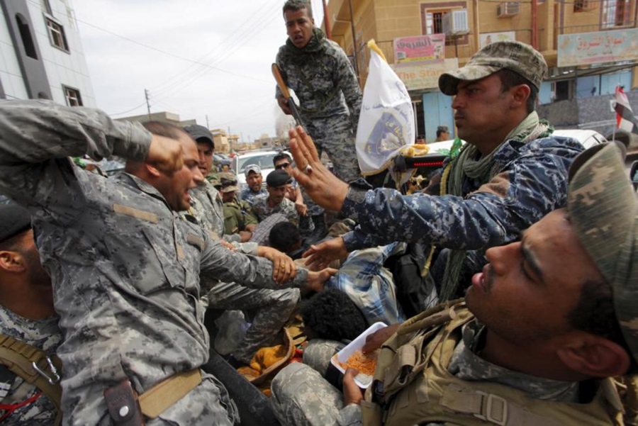 ReutersA serviceman from the Iraqi security forces punches an Islamic State insurgent who was captured in Tikrit