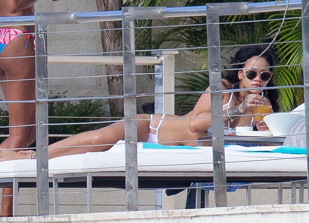 Winter break Rihanna has jetted off to her native Barbados and was seen kicking back with friends as she sunbathed on the deck of a beautiful villa on Monday afternoon