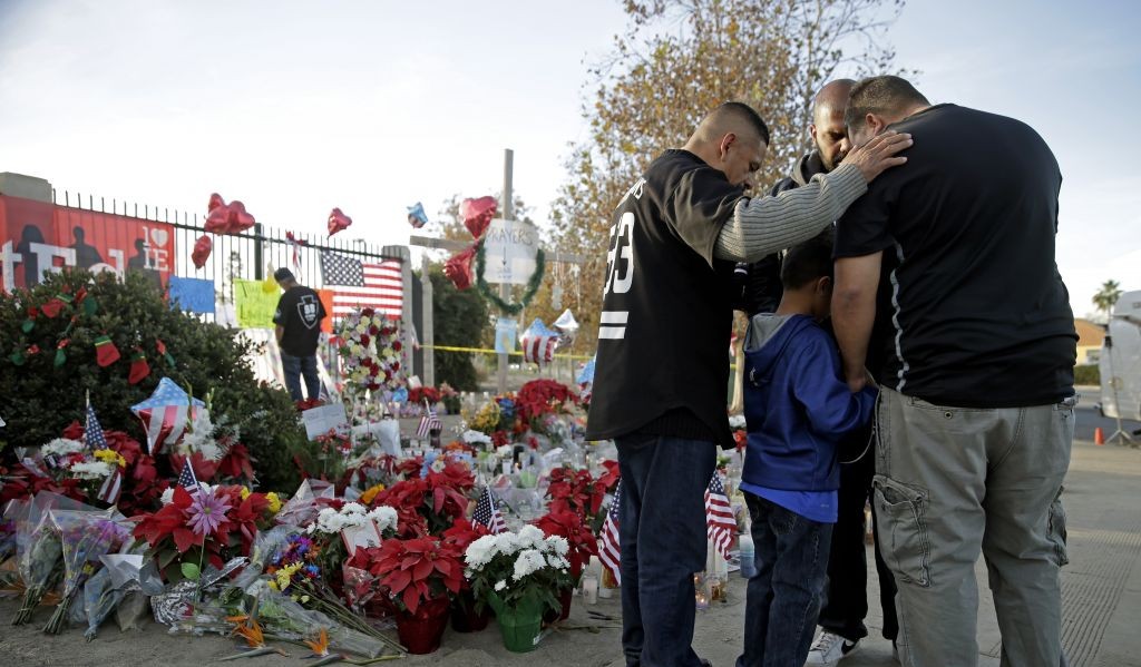 Mourners comfort each other at a makeshift memorial site honoring Wednesday's shooting victims Monday Dec. 7 2015 in San Bernardino Calif. Thousands of employees of San Bernardino County are preparing to return to work Monday five days after a