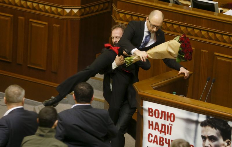 Rada deputy Oleg Barna removes Prime Minister Arseny Yatseniuk from the tribune after presenting him a bouquet of roses during the parliament session in Kiev Ukraine. – Reuters pic