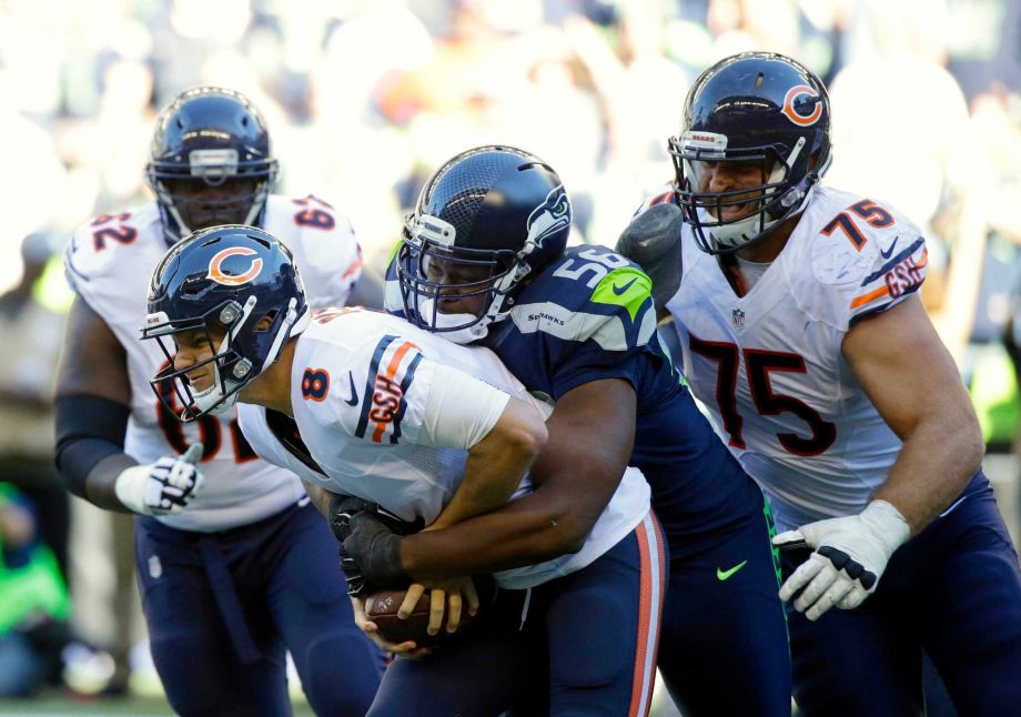 Seattle Seahawks defensive end Cliff Avril tackles Chicago Bears quarterback Jimmy Clausen as Bears Kyle Long looks on in the second half of an NFL football game Sunday Sept. 27 2015 in Seattle. The Seahawks beat the Bears 26-0. (AP