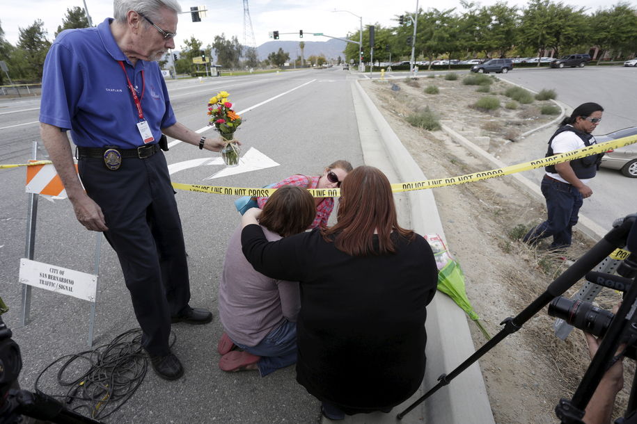 People including a woman identified as the fiancee of a murder victim in Wednesday's attack brings flowers to the scene of the attack in San Bernardino California