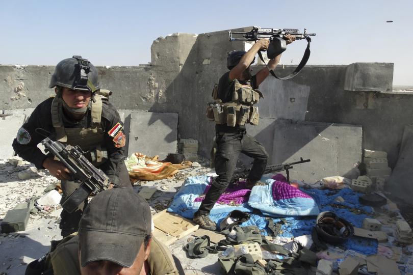 Iraqi troops take cover on a roof in Ramadi