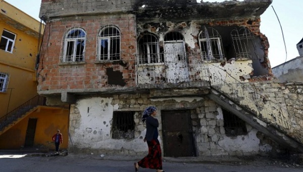 A woman walks past a building damaged during clashes between Turkish security forces and Kurdish militants in the southeastern town of Silvan Turkey Dec. 7 2015