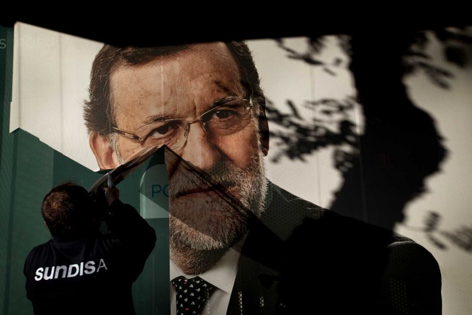 A worker removes a campaign poster for the national elections depicting Spain's acting Prime Minister and Popular Party candidate Mariano Rajoy in Madrid Monday Dec. 21 2015. Spanish political parties Monday faced what are likely to be tough negotiati