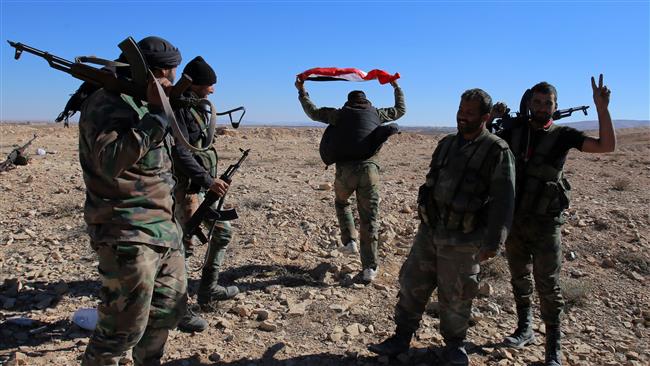 Syrian pro-government forces flash the V sign for victory and wave the Syrian flag as they gather on a hilltop they took over near the town of Mahin Homs Province