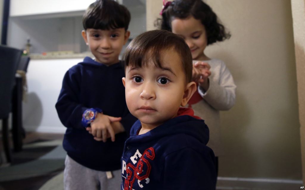 Syrian refugee Mohammad word al Jaddou front stands in front of his siblings twins Maria right and Hasan at their apartment in Dallas