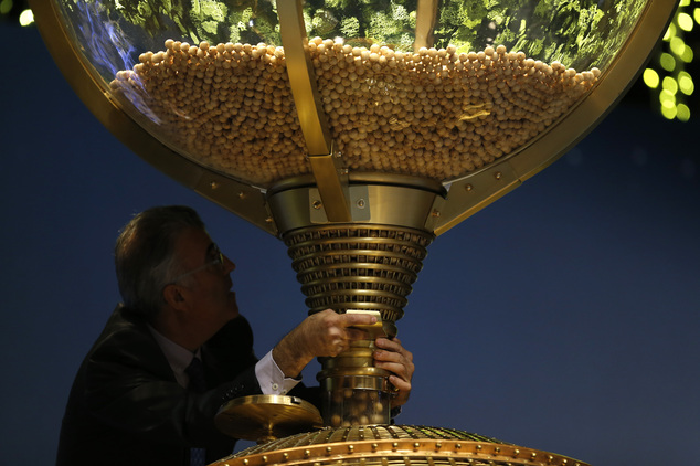 A worker opens a trap-door in a giant drum to let the balls bearing ticket numbers fall into a lower compartment before the start of Spain's Christmas lotter