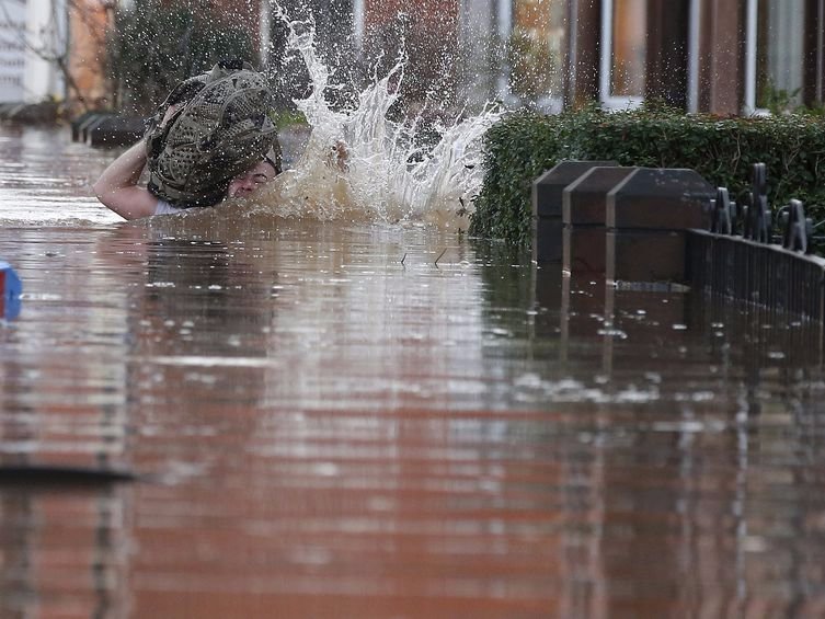 A local resident stumbles as he wades through flood water on a residential street in Carlisle Britain