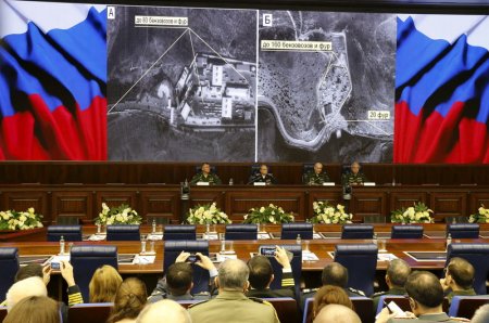 Defence ministry officials sit under screens with satellite images on display during a briefing in Moscow Russia