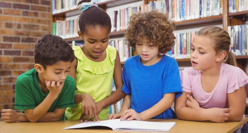 039;Elementary school students reading from a book&#039