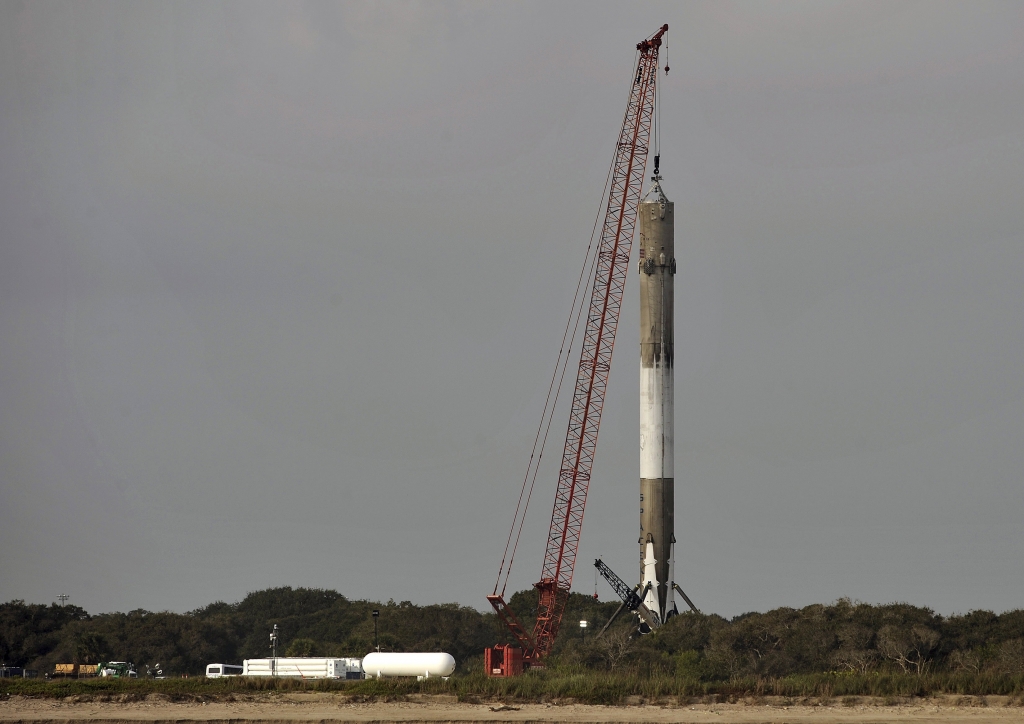 A crane steadies the SpaceX Falcon 9 booster rocket as it rests on a landing zone near the Atlantic Ocean in Cape Canaveral Florida