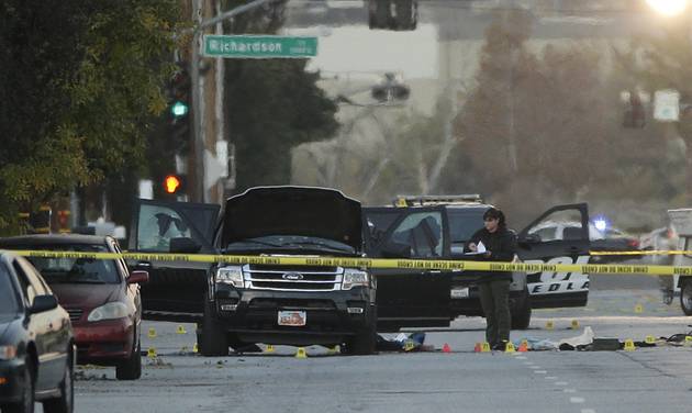 An investigator looks at a Black SUV that was involved in a police shootout with suspects Thursday Dec. 3 2015 in San Bernardino Calif. A heavily armed man and woman opened fire Wednesday on a holiday banquet killing multiple people and seriously