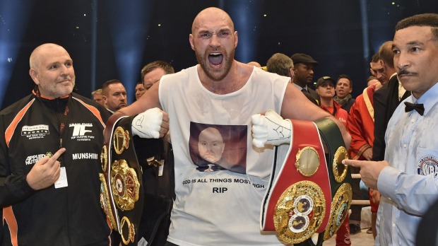 Ecstatic Britain's new world champion Tyson Fury celebrates with the WBA IBF WBO and IBO belts