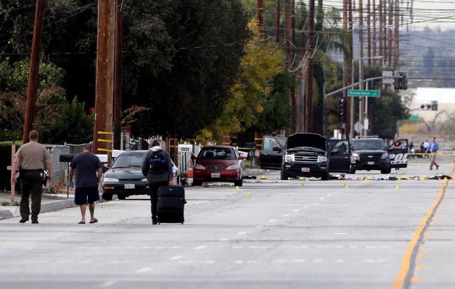 Residents are escorted to their home near a Black SUV that was involved in Wednesday's police shootout with suspects Thursday Dec. 3 2015 in San Bernardino Calif. A heavily armed man and woman dressed for battle opened fire on a holiday banquet for