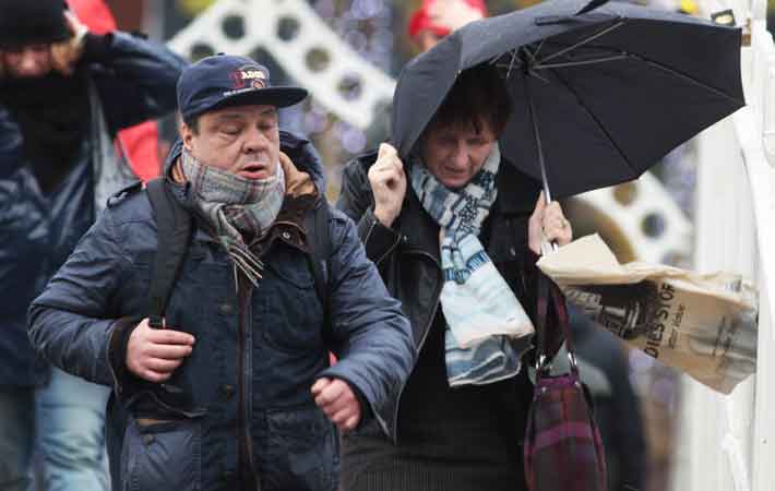 Members of the public cross the Ha'penny Bridge as they make their way around Dublin City Centre in the rainy and windy weather