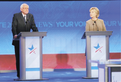 Democratic U.S. presidential candidate and former Secretary of State Hillary Clinton looks over at U.S. Senator Bernie Sanders as he is questioned about the campaign data breach scandal during the Democratic presidential candidates debate at St. Anselm Co