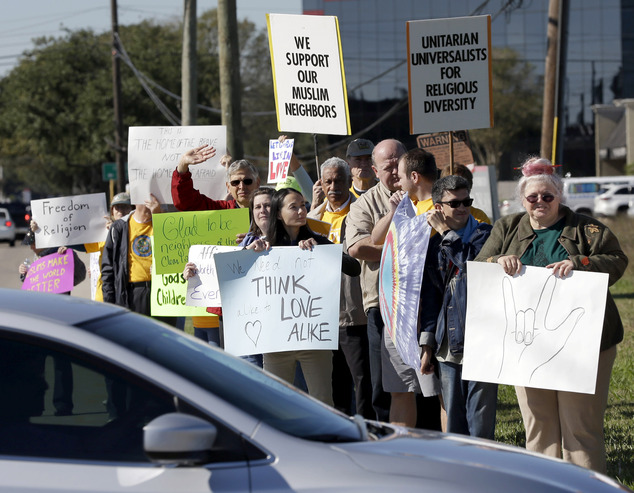 People hold signs during a rally to show support for Muslim members of the community near the Clear Lake Islamic Center in Webster Texas on Friday Dec. 4