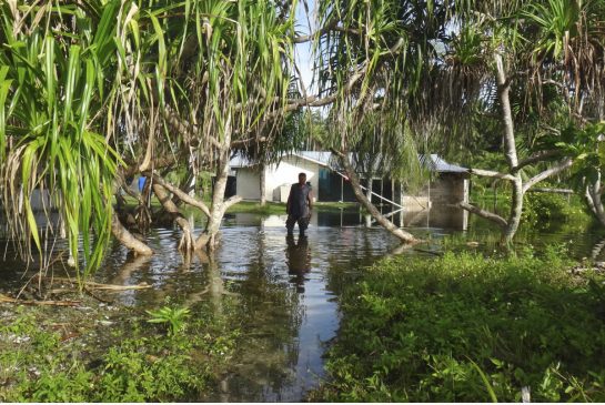 A man walks through knee-deep water to reach his home during a king tide event on Kili in the Marshall Islands. Some islands such as the Marshall Islands and the Maldives are all examples of dangerously low-lying territories expecting to be mostly underwa