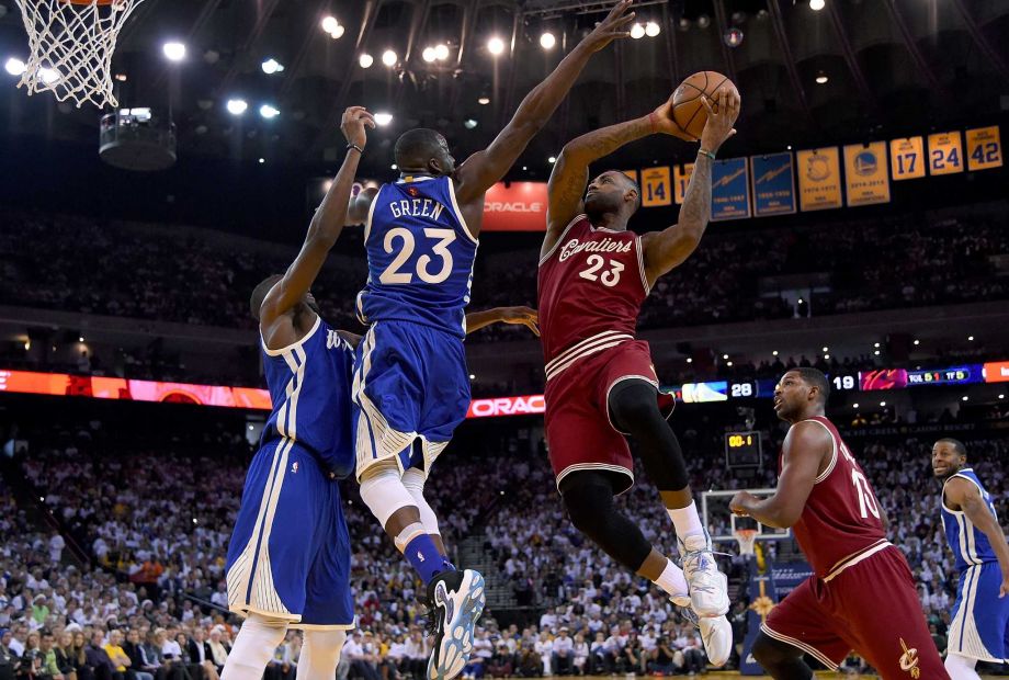 OAKLAND CA- DECEMBER 25 Le Bron James #23 of the Cleveland Cavaliers looks to get his shot off over Draymond Green #23 of the Golden State Warriors during their NBA basketball game at ORACLE Arena