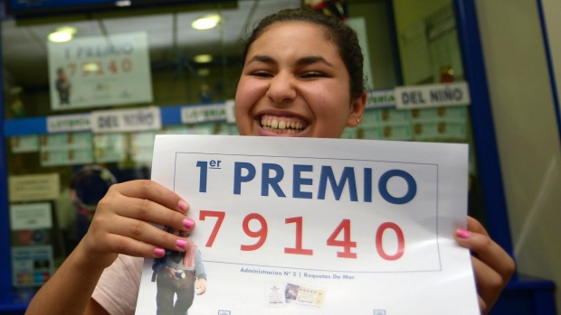 Winner Imanes Naamane celebrates as she holds a placard showing the first prize winning number 79140 of Spain's Christmas Lottery'El Gordo