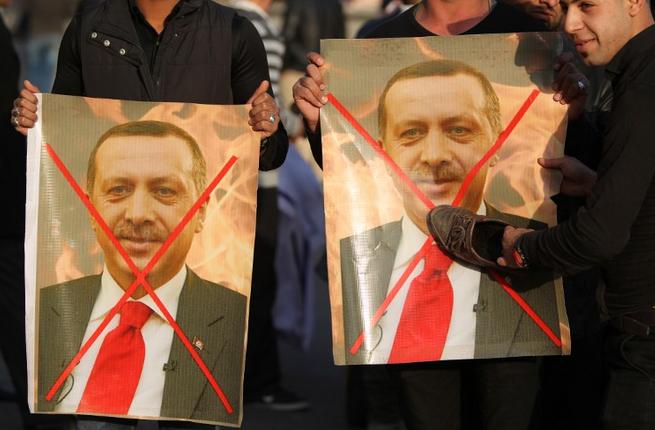 Iraqis hold crossed-out portraits of Turkey's President Recep Tayyip Erdogan during a demonstration in Baghdad's Tahrir Square