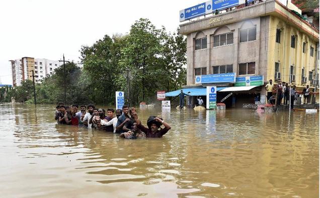 Flood affected people shift from an inundated locality following rains at Porur in Chennai on Wednesday