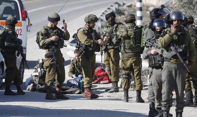 Israeli soldiers work around the body of a Palestinian assailant after he was shoot dead in the West Bank city of Hebron Thursday Dec. 24 2015. The Israeli military said the man wielding a screwdriver was shot dead after he tried to stab security