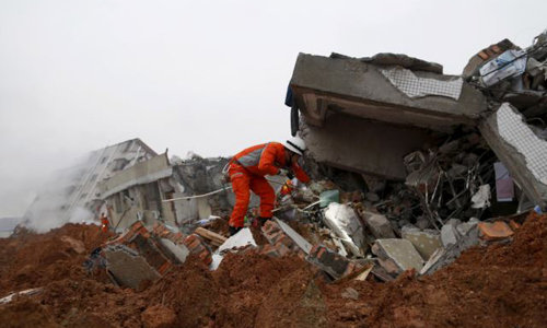 A firefighter uses a flashlight to search for survivors among the debris of collapsed buildings after a landslide hit an industrial park in Shenzhen Guangzhou on Dec. 20 2015. /Reuters