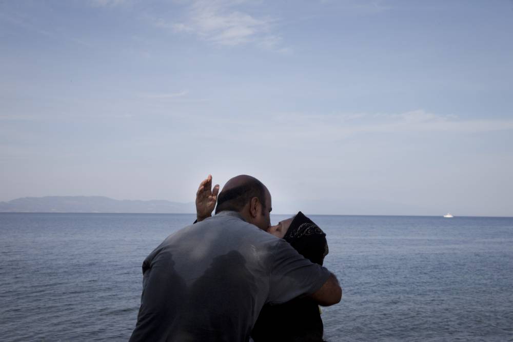 Sept. 9 2015 a woman and a man kiss after their arrival on a dinghy with other migrants and refugees from the Turkish coast to the northeastern Greek island of Lesbos. An