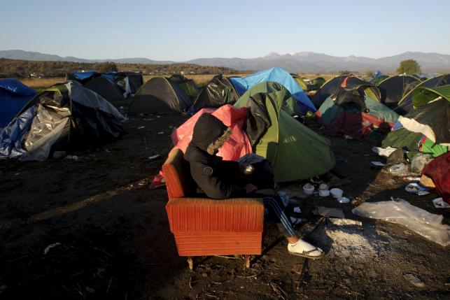 A stranded migrant sits on a sofa next to a make shift camp at the Greek Macedonian border near the village of Idomeni Greece