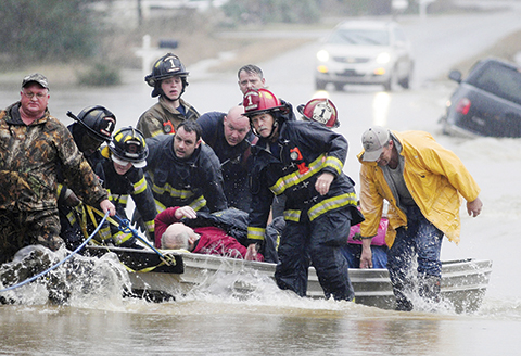 Emergency officials transport James Simmons by boat because water over Byler Road prevented them from reaching him in Moulton Ala. Friday Dec. 25 2015. They carried him by boat before loading him into an ambulance. Unseasonably warm weather helped spa