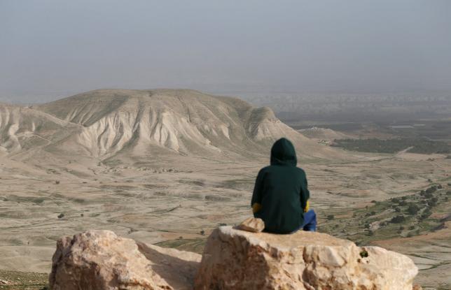 A Palestinian man sits on a rock at Jordan Valley near the West Bank city of Jericho